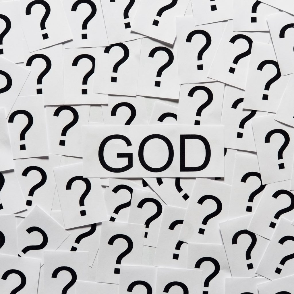 Word "god" on a pile of papers with question marks