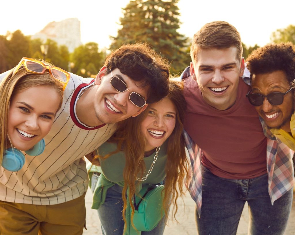 Group of smiling young people with their arms around each others shoulders